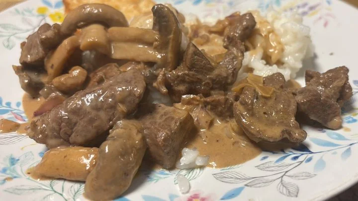 Kotitekoinen naudanlihastroganoff valkoisen riisin kera, jossa on lihanpaloja ja herkkusieniä kermasinappikastikkeessa.