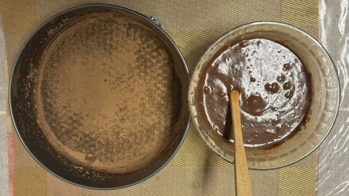 Kaakaolla jauhotettu irtopohjavuoka ja kulho, jossa on suklaakakkutaikinaa.