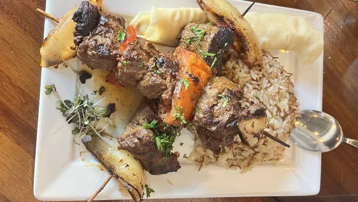 Grillspetten med köttärningar direkt från elden, med lök och tomat mellan bitarna, serverade med ris och lavashbröd