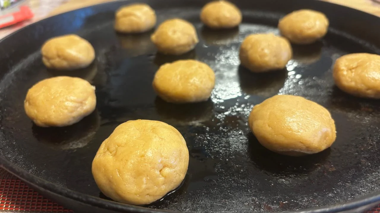 Bolinhas de massa de prianik organizadas em uma assadeira escura
