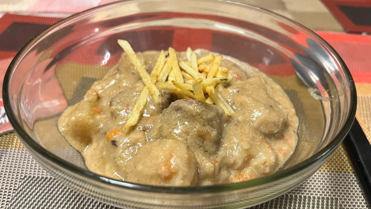 Sopa de amendoim encorpada com pedaços de carne, coroada com batata palha
