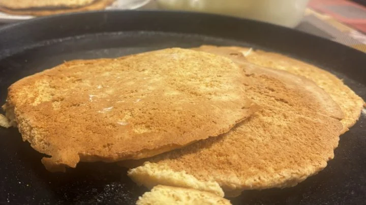 Los discos de masa recién horneados sobre la fuente, con el bol de crema de yogur griego y la torta empezando a armarse al fondo