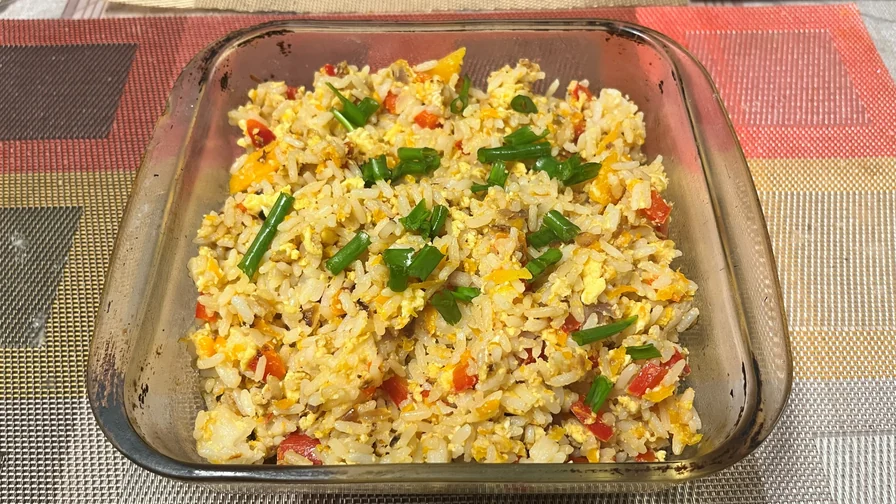 Arroz frito com ovo, pimentão e cebolinha, servido em uma travessa de vidro