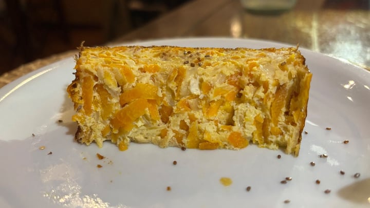 En skive gulerodsgratin med ost på en hvid tallerken, med chiafrø